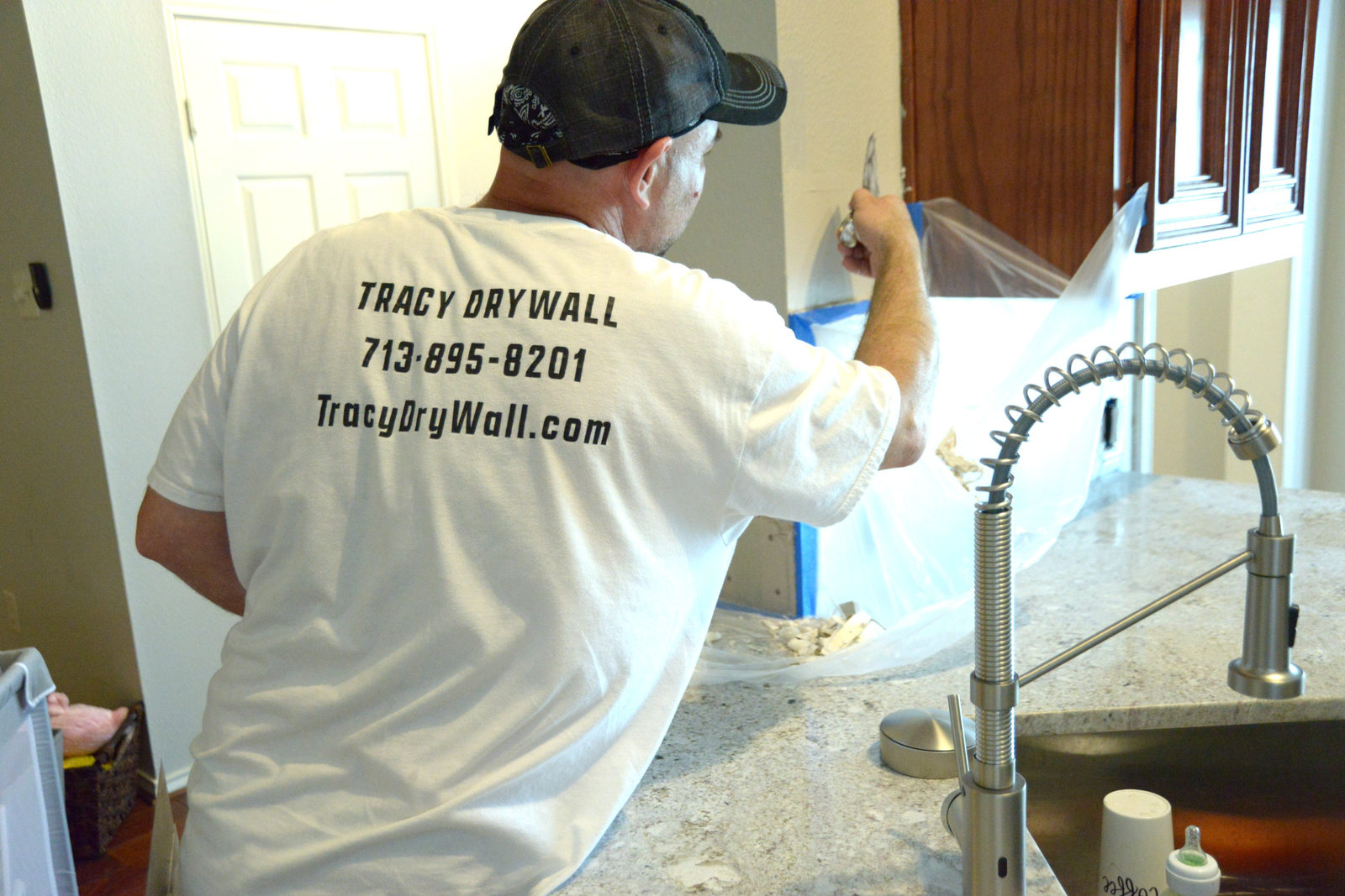 Tracy Drywall craftsman at work in a Tracy Drywall shirt